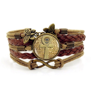 Close-up of bronze Ankh pendant and butterfly charms on multi-layer leather bracelet