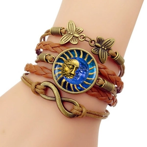 Détail d'un bracelet bohème multicouche en cuir avec breloques en bronze et dôme de verre