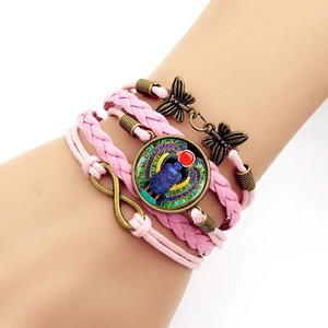 Detail of pink layered braided leather bracelet with Egyptian beetle and butterfly charms