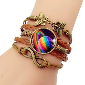 Détail macro du bracelet multicouche en cuir avec cabochon en verre galaxie et breloques