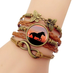Détail d'un bracelet multicouche en cuir avec breloques papillon et signe infini