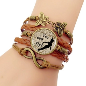 Détail du bracelet en cuir tressé multicouche avec breloques vintage et Peter Pan