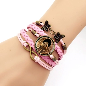 Détail de bracelet multicouche en cuir rose avec scarabée en bronze et breloques papillon