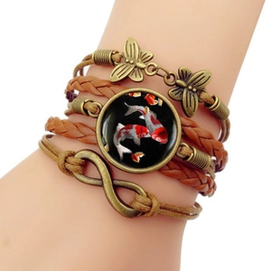 Macro view of vintage multilayer leather bracelet with bronze butterfly and koi fish glass dome