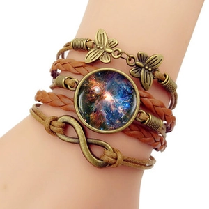 Detail of bohemian multilayer leather bracelet with bronze butterfly charms and galaxy gem