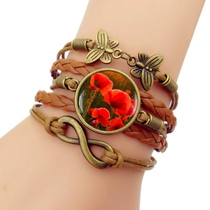 Detail showing multi-layer leather bracelet with bronze charms and poppy flower pendant