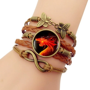 Detail of vintage multilayer braided bracelet with infinity symbol and red dragon pendant