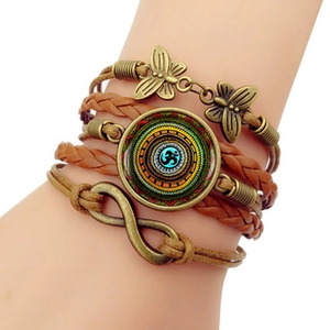 Detail view of retro multilayer leather bracelet with bronze butterfly and Om charms