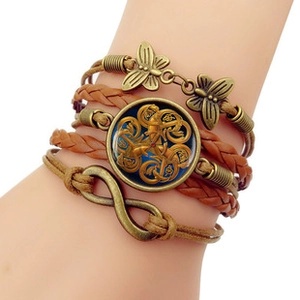 Detail of vintage layered leather bracelet with bronze butterfly and infinity symbol charms