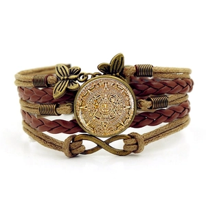 Macro detail of Aztec calendar glass gem on multilayer woven leather bracelet craft