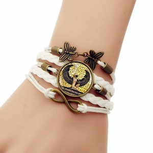 Detail of multi-layer white leather bracelet with bronze butterfly and Egyptian pendant