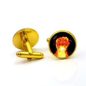 Detailed view of gold cufflinks featuring a red flame fist design on a black background