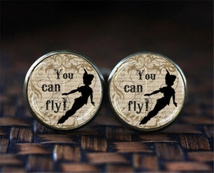 Macro shot of vintage bronze cufflinks featuring Peter Pan silhouette and You can fly text
