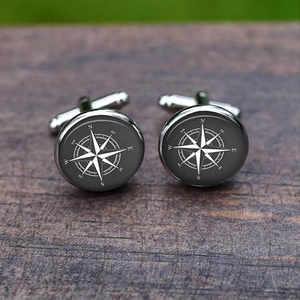Detailed close-up of vintage silver compass cufflinks on a dark wooden background