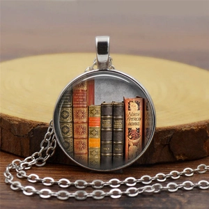Macro shot of vintage library book art pattern inside a silver-tone glass pendant necklace