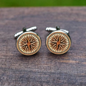 Vintage silver compass cufflinks for men's shirts on a natural dark wood background