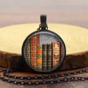 Macro view of vintage library books pendant with antique glass gem and black metal frame
