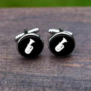 Macro shot of silver cufflinks with white tuba musical pattern on black background