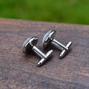 Elegant silver cufflinks with round design on dark wood background with nature view