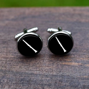Macro shot of silver cufflinks featuring a white clarinet silhouette on a black background