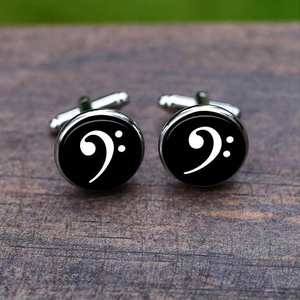 Macro shot of silver cufflinks with bass clef music symbol on black glass background