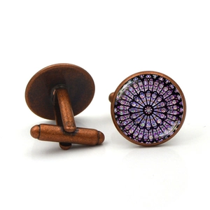 Macro view of vintage bronze cufflinks featuring purple gothic rose window patterns