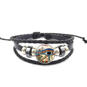 Détail macro du cabochon œil d'Horus et des perles de cuir tressé sur le bracelet