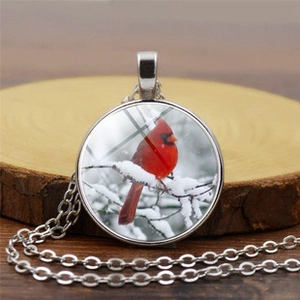 Detail of cardinal bird pendant necklace on a rustic wooden tray with silver chain link