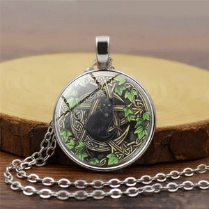 Detail of vintage compass necklace with black cat and gold pentagram on wood