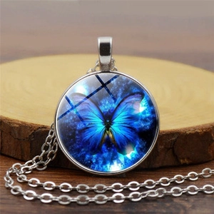 Close-up of vintage round glass pendant necklace with blue butterfly pattern