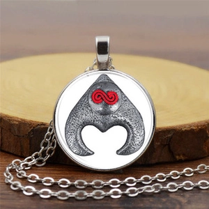 Detailed macro of vintage silver compass pendant with red infinity symbol and metal chain