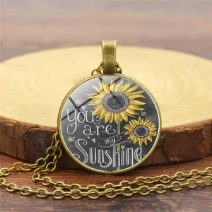 Collar retro con colgante de girasol y texto 'You are my sunshine' sobre madera