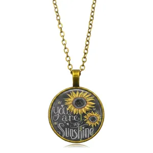 Vista detallada del colgante retro de girasol con la frase You are my Sunshine grabada