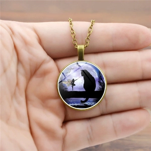 Close-up of bronze necklace with black cat and fairy silhouette on purple moon night