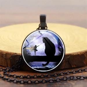 Detailed macro view of the black cat and fairy glass gem pendant on a rustic wood slice