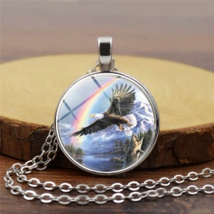 Gros plan du pendentif cabochon en verre avec motif d'aigle et paysage montagneux
