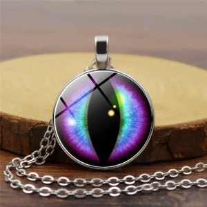 Détail du pendentif en verre steampunk avec œil de dragon violet sur bois rustique