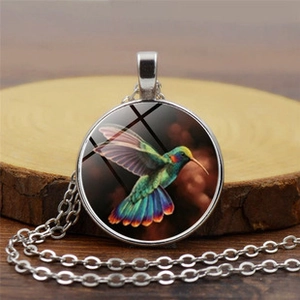 Vue macro du pendentif steampunk argenté avec cabochon en verre orné d'un colibri coloré