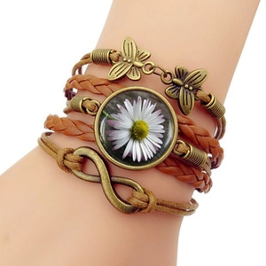 Détail du bracelet multicouche en cuir rétro avec papillons en bronze et breloque marguerite