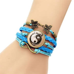 Vue détaillée du bracelet en cuir tressé bleu avec charmes papillon et pendentif loup yin yang