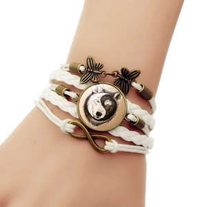 Détail du bracelet en cuir tressé avec breloques papillon et pendentif loup en verre