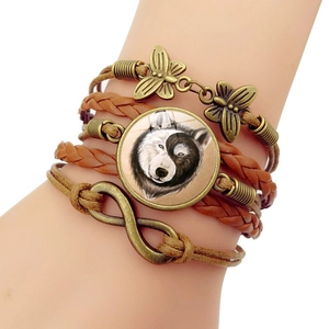 Détail d'un bracelet en cuir multicouche avec pendentif loup en verre et breloque papillon bronze