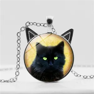 Detail shot of a black cat pendant with vibrant green eyes and distinct metal cat ears