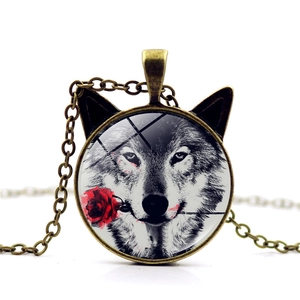 Close-up of bronze wolf head necklace with glass pendant and red rose watercolor art