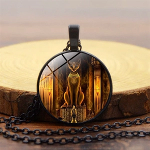 Detail shot of Bastet Egyptian cat god time gem necklace on a round wooden display base