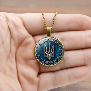 Vintage bronze necklace featuring Ukraine trident symbol on blue wood grain background