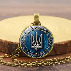 Macro detail of bronze trident necklace with glass cabochon on a rustic wood background