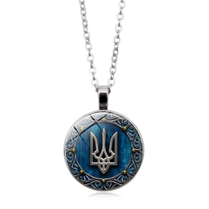Ukraine Trident Tryzub glass pendant necklace with vintage silver chain on blue wood background