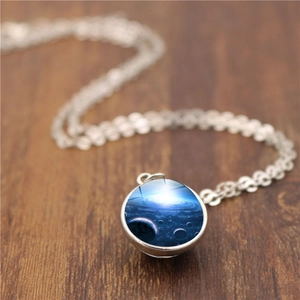Gros plan d'un pendentif en verre galaxie cosmique sur une chaîne en argent fin