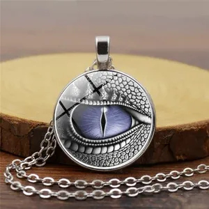 Detailed view of owl-themed necklace with purple dragon eye glass pendant on wooden base
